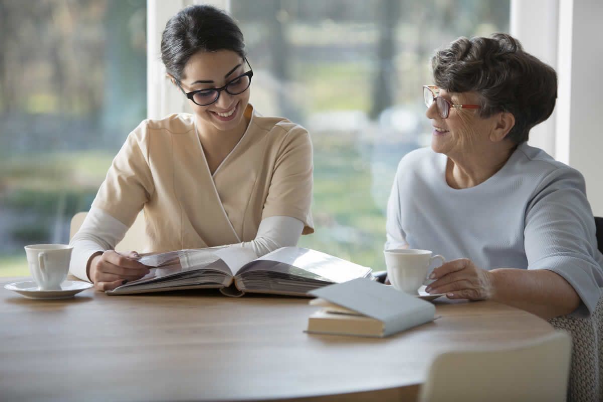 A caregiver reading with a client at the kitchen table